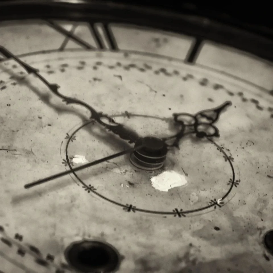 Close-up of an antique clock face with ornate hands and weathered texture.